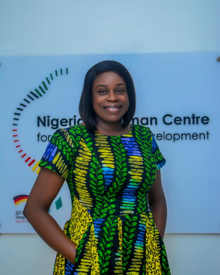  A woman (Eseosa Okuku) wearing a colourful dress smiles into the camera. 