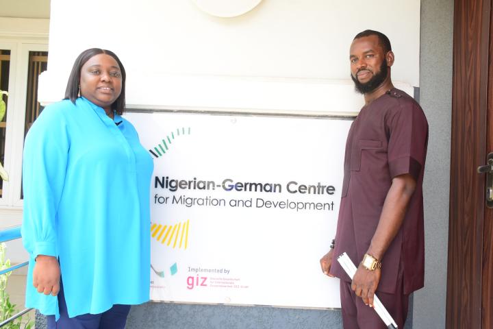  A woman and a man stand in front of the entrance of the Nigerian-German Centre for Migration and Development. 