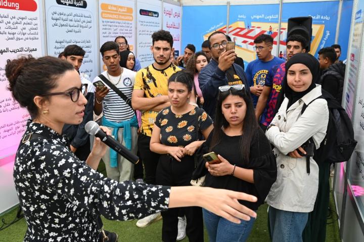 A young woman with a microphone speaks to a group of people   A young woman with a microphone speaks to a group of people